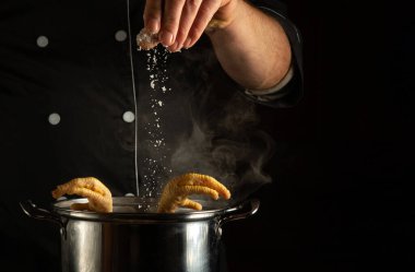 Aşçı tavaya kaynar tavuk bacağı ile tuz döker. Lokanta mutfağında lezzetli bir çorba hazırlama fikri..