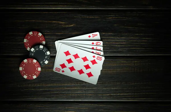 A very gambling game of poker with a winning combination of a royal flush. Cards with chips on a dark vintage table in a poker club. Black space for advertising.