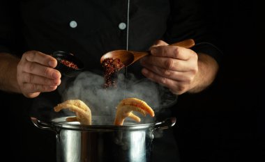 Şef mutfakta tavada lezzetli tavuk çorbası hazırlıyor. Aşçının elinde kaşıkla kuru baharat ekliyorum..