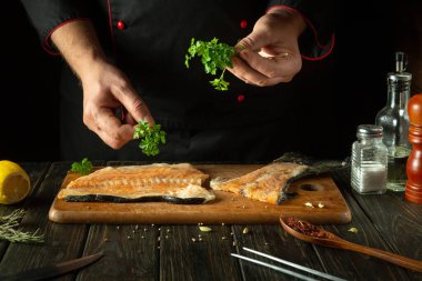 Otel mutfağında maydanozlu alabalık bifteği çeşnilendiren bir balık şefi. Pembe somon, akşam yemeği hazırlamak için lezzetli bir balıktır. Asya mutfağı.