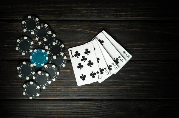 A very gambling game of poker with a winning straight flush combination. Cards with chips on a dark vintage table in a poker club. Dark space for advertising.