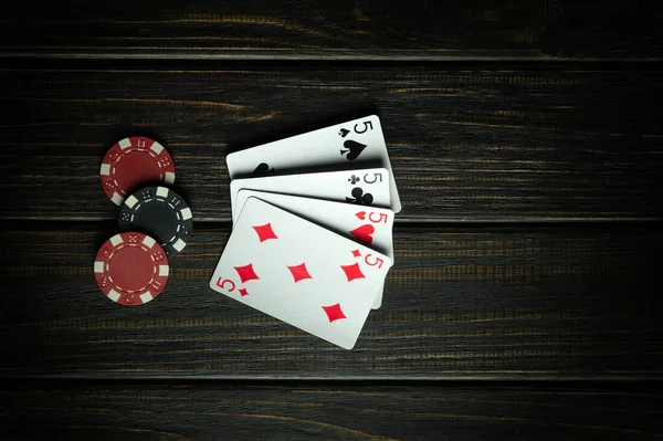stock image A very gambling game of poker with four of a kind or quads. Red chips and cards on a dark vintage table in a poker club.
