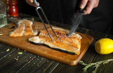 Mutfak masasında bir şefin elleriyle baharatlı balık bifteği hazırlama süreci. Reklam alanı