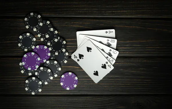 A very gambling game of poker with a winning combination of high cards. Cards with black and purple chips on a dark vintage table in a poker club.