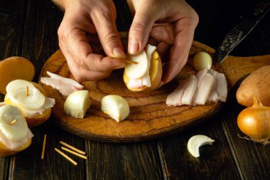 Izgarada pişirmeden önce mutfak masasında çiğ patates, soğan ve domuz yağı hazırlayan şefin yakın çekimi. Lezzetli fast food konsepti.