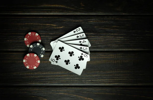 A poker game of chance with a winning straight-flush combination. Cards with chips on a dark vintage table in a poker club. Free space for advertising