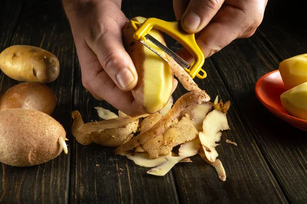 Şef patates soyacağı kullanarak öğle yemeği ya da patates kızartması hazırlıyor. Bir restoran için lezzetli sebze diyeti konsepti.