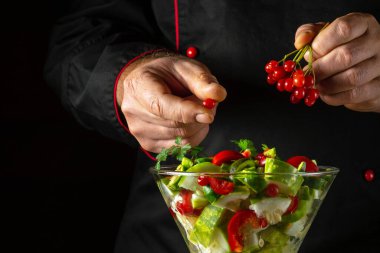 Aşçı öğle yemeği için vitamin salatasına kırmızı viburum ekler. Bir şefin elleriyle vejetaryen yemeği hazırlama fikri.
