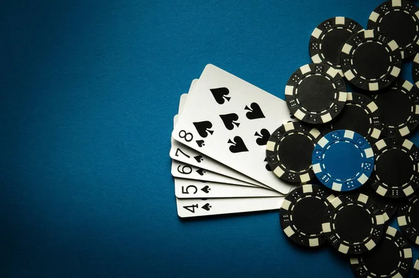 A gambling game of poker with a winning combination of straight flush. Cards with chips on a blue table in a poker club. Advertising space.