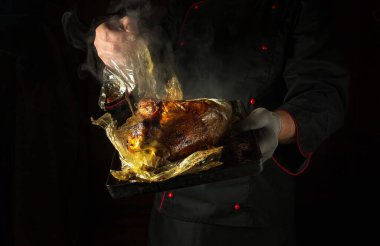 Aşçı pişirdikten ya da pişirdikten sonra plastik keseyi tavuktan elle çıkarır. Restoran mutfağında horoz kızartma fikri. Reklam için siyah alan.