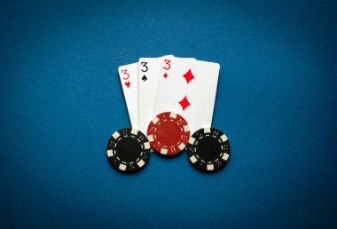 Üçlü ya da set kombinasyonlu poker oyunu. Fişler ve kartlar mavi masada poker masasında.