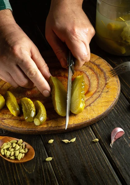 A cook uses a knife to cut pickles on a kitchen board to prepare a salad for lunch. Concept of preparing diet food or vegetable menu