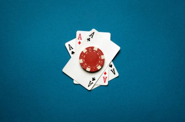 Amerika 'da popüler bir poker oyunu. Üçü bir arada. Fişler ve aslar poker kulübünde mavi bir masada kağıt oynuyorlar..