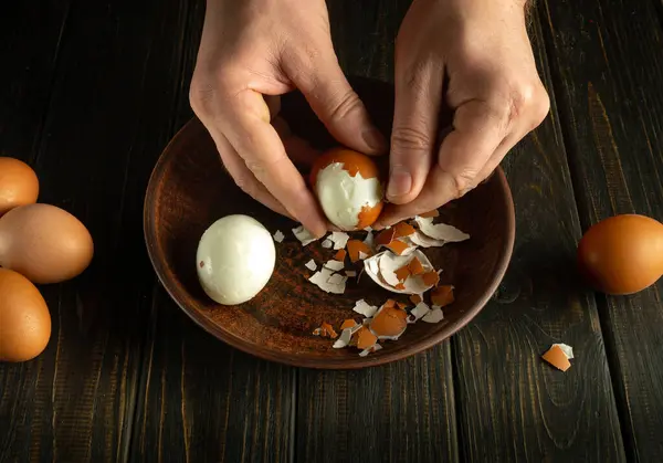 Chef hands peeling eggs on the kitchen table. Close-up of male hands peeling a boiled egg from its shell.