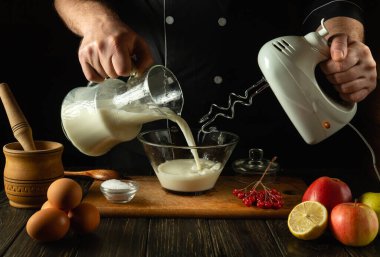 Şef, el yapımı elektrikli mikser kullanarak mutfakta meyveli bir milkshake hazırlıyor. Aşçı derin bir tabağa süt döker. Bir otel ya da restoran için lezzetli tarifler menüsü.