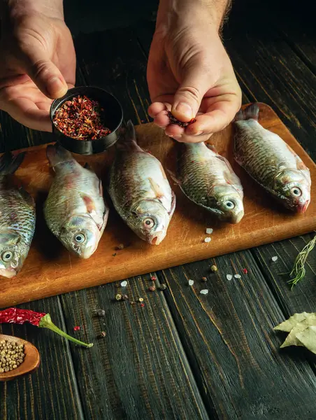 The cook marinates fish with aromatic spices and coriander on the kitchen table. Advertising space.