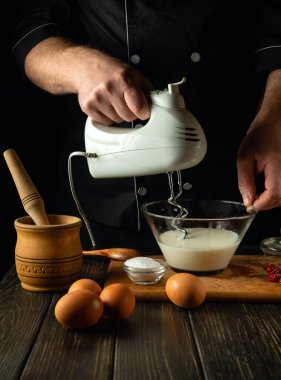 Şef mutfakta yumurta ve sütle birlikte bir yemek tabağı hazırlıyor. Restoranda ya da otelde, mutfak masasında lezzetli bir öğle yemeği hazırlama fikri.