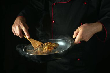 Bir şef restoran mutfağında nehir balığı hazırlar. Sazanı kızartma tavasında kızart. Lezzetli bir balık diyeti fikri.