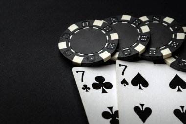 Kumarhanede kazanan tek çiftli poker kartları. Fişler ve kartlar siyah masada..