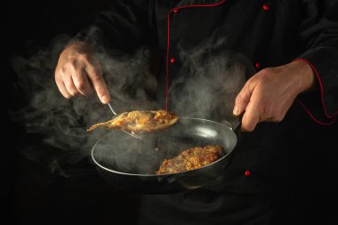 Restoran mutfağında sazan balığı pişirmek. Balığı kızartma tavasında bir şefin ellerinde pişir. Öğle yemeği için lezzetli bir balık yemeği hazırlama kavramı..