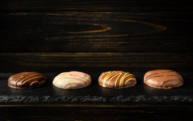 Çikolatalı kurabiye ya da siyah servis tahtasında çikolatalı kek. Otel için lezzetli tatlı konsepti. Milyoner kurabiyesi fikri. Reklam alanı.