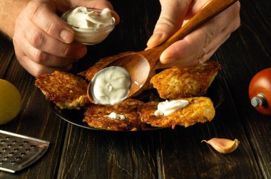 Şefin elinde ekşi kremalı kaşık. Patatesli krep ve ekşi kremayla atıştırmalık bir şeyler hazırlıyorum. Gıda hizmeti kavramı.