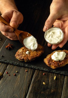 Şefin eli, servis panosundaki et pirzolalarına ekşi krema ekliyor. Lezzetli et yemeği konsepti. Reklam alanı.