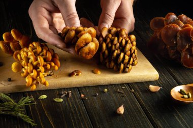 Mutfak masasında bir aşçının elleriyle mantar pişirmek. Aşçı pişirmeden önce mantar ayırıyor..