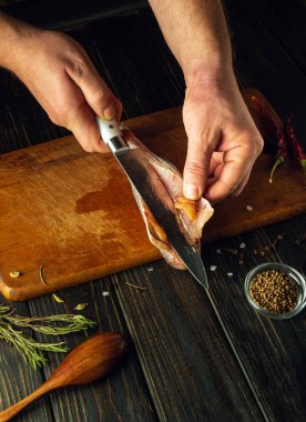 Bir şefin elinde bıçakla donmuş balığı filetoya dönüştürmek. Restoranda mutfak masasında balık tabağı pişirmek.