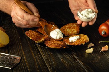 Patatesli krep ve ekşi krema ile öğle yemeği için lezzetli bir yemek hazırlıyorum. Yemek servisi yaparken bir adamın elinde kaşık. Reklam alanı.