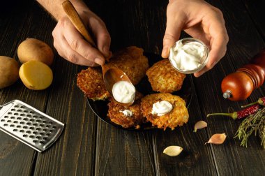 Şefin ellerini bir tabakta krepe ekşi krema eklemek için kaşık kullanarak yakın plan çek. Vejetaryen yemeği konsepti.