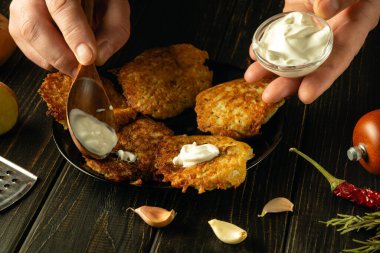 Patatesli gözlemelere bir şefin elleriyle lezzetli bir tat katmak için ekşi krema ekliyorum. Bir ziyafette lezzetli bir sebze yemeği sunma süreci..