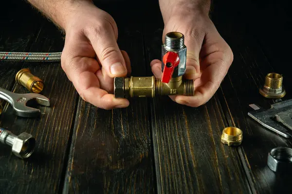 Repairing plumbing by hands. Hands of a craftsman connect a plumbing faucet and brass fittings. Advertising space.