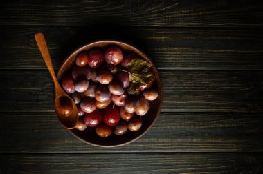 Köy ahşap bir masada baharatlı turşu dolu klasik erik kasesi. Vejetaryen gıda konsepti veya köylü yemeği.