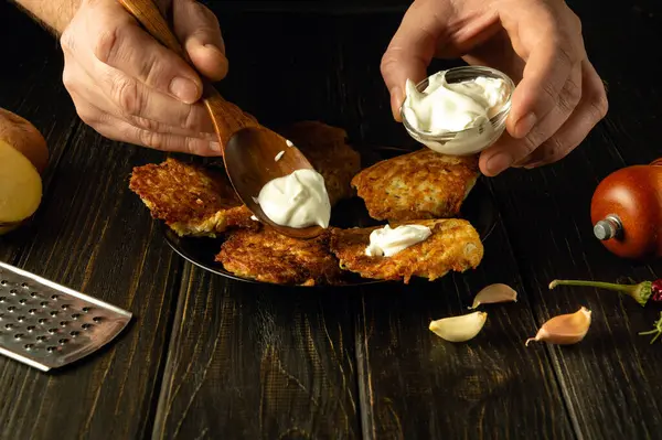 Erkek eller, tabakta kızarmış patatesli krepe ekşi krema ekler. Evde lezzetli yemekler hazırlama kavramı. Reklam alanı.