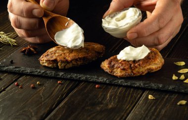 Ekşi kremalı pirzolalardan kahvaltı için bir et yemeği hazırla. Yemek servisi yaparken bir adamın elinde kaşık. Reklam alanı