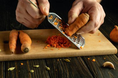 Mutfak masasında sebze tabağı hazırlıyorum. Şefin elleri diyet yemeği için havuç rendeliyor..