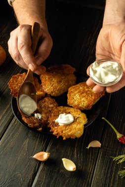 Aşçı ellerinin bir tabakta krepe ekşi krema eklemek için bir kaşık kullanarak yakın plan çekimleri. Vejetaryen kahvaltı konsepti.