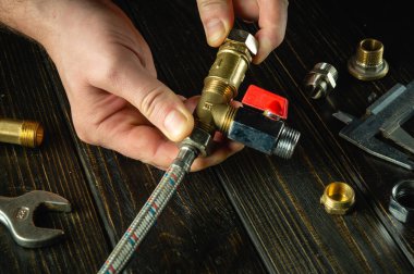 Yüksek basınçlı su hortumunu pirinç tesisatlara bağlayan usta bir tesisatçı eli. Evde su tesisatı tamir etme kavramı.