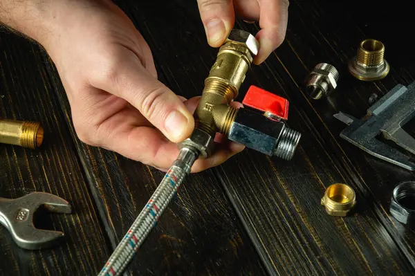 Yüksek basınçlı su hortumunu pirinç tesisatlara bağlayan usta bir tesisatçı eli. Evde su tesisatı tamir etme kavramı.