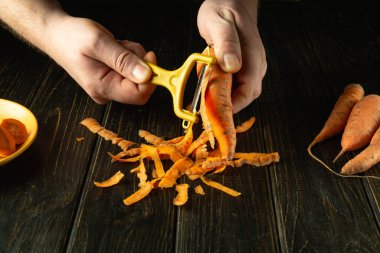 Bir şef ulusal kahvaltı yemeği hazırlamak için havuç soymak için sebze soyacağı kullanır. Lezzetli sebze diyeti konsepti.