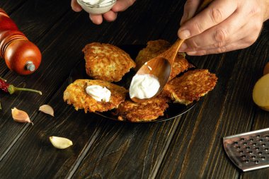 Aşçı ekşi kremalı patates gözlemesi ile lezzetli bir yemek hazırlar. Aşçının elinde ekşi kremalı kaşık. Lezzetli kahvaltı için gösterişsiz bir konsept.