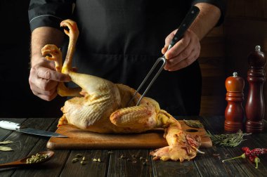 Bir restoranın ya da barın mutfağında bir aşçının elinden çiğ tavuk. Kesme tahtasında çiğ horoz pişirmeye hazırlanıyorum. Şefin elini çatalla..