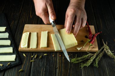 Şefin elleri Mozzarella peynirini dilimlemek için bir bıçak kullanır. Lezzetli bir sütlü peynir tarifi sunuyorum..