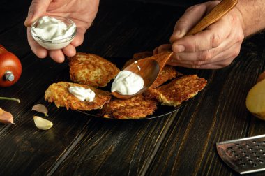 Ekşi kremalı patatesli krepten akşam yemeği için lezzetli bir yemek hazırlıyorum. Aşçının elinde ekşi kremalı kaşık. Tarif veya menü için boşluk.