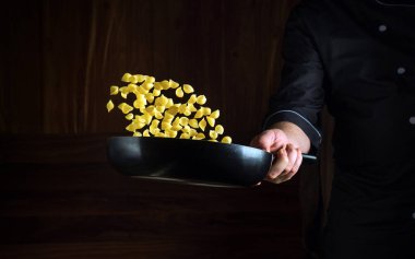 Bir şef bir meyhanenin mutfağında makarna hazırlar. Bir aşçının elindeki tavanın üzerinden makarna uçuşu..