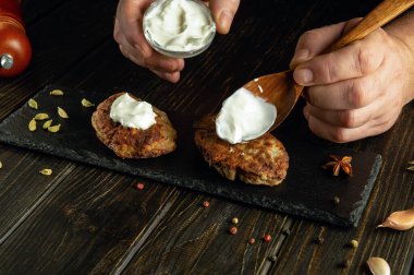 Aşçı mutfak tahtasında ekşi kremalı et pirzolası hazırlıyor. Lezzetli bir öğle yemeği hazırlama konsepti.