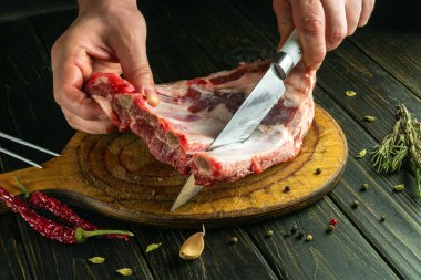 Et yemeği hazırlamadan önce şef, et kesme tahtasındaki bir bıçakla çiğ kaburga keser. Salon için sade bir tarif fikri.