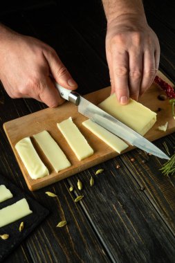 Şef, sofra kurmak için Mozzarella peynirini ince şeritlere ayırmak için bıçak kullanıyor. Yemekte mandıra servisi yapmanın gösterişsiz bir konsepti..