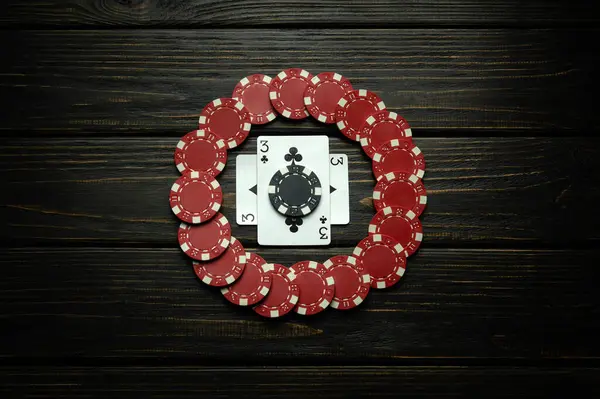Red chips and playing cards with a winning combination of one pair on a black vintage table. Low key concept of luck or winning in poker club.